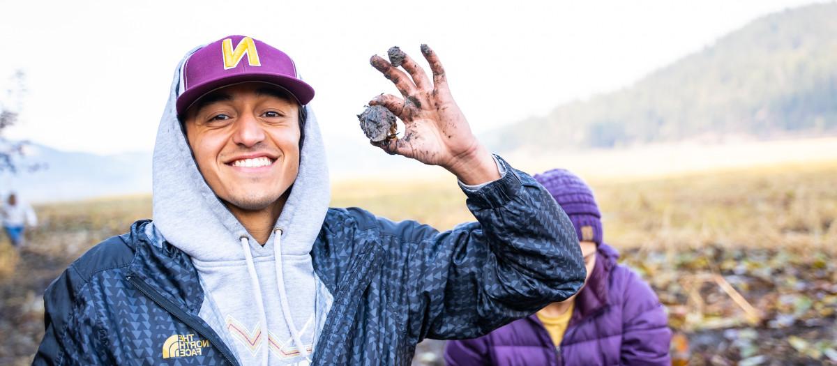 person holding a small and muddy potato