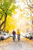 Two students ride down Greek Row in the f所有, amid changing leaves.