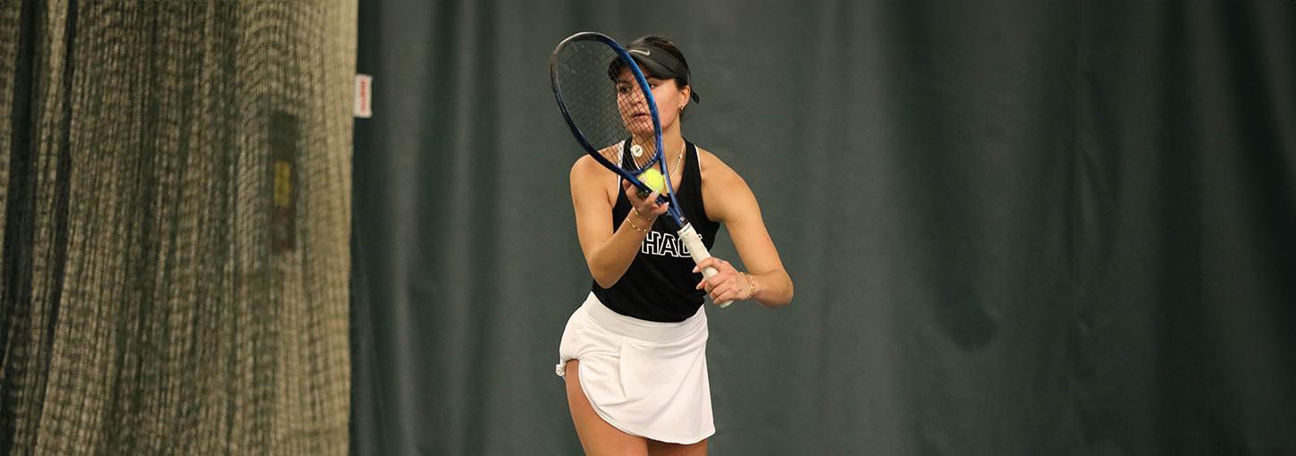 Woman tennis player preparing to serve ball.